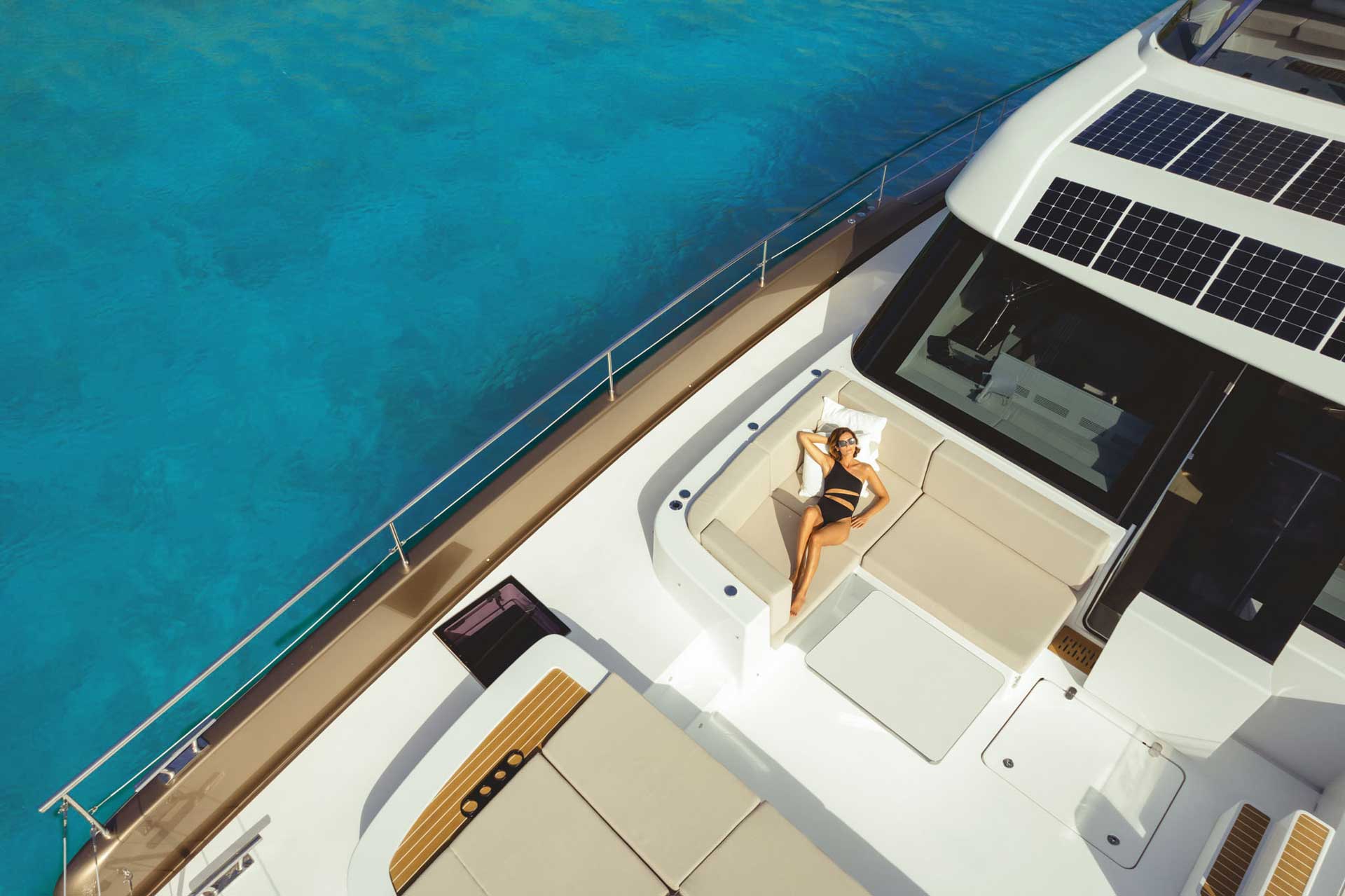 DJI_0503 A person lounging on the deck of a Sunreef Yachts catamaran with turquoise waters in the background.