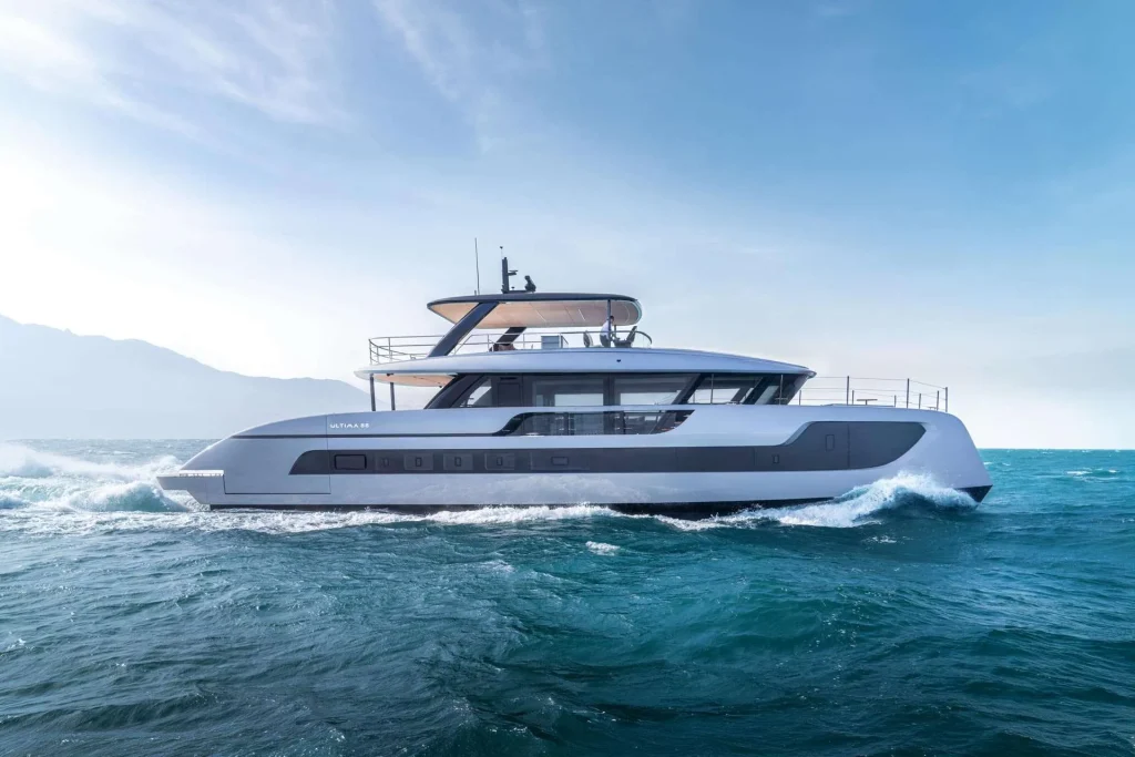 A luxury catamaran by Sunreef Yachts gliding through the blue ocean with a clear sky above.
